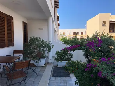 an outdoor patio with flowers and a table and chairs at Case Vacanza appartamenti Trinacria in San Vito lo Capo