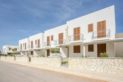 a large white house with a stone wall at Case Vacanza appartamenti Trinacria in San Vito lo Capo