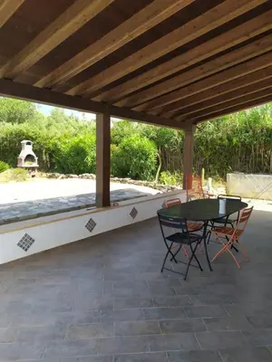 a patio with a table and chairs under a wooden roof at Antico Rustico in Scopello