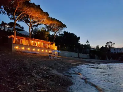 a train with lights sitting on a beach at night at Brezza Marina Guesthouse in Cefalù