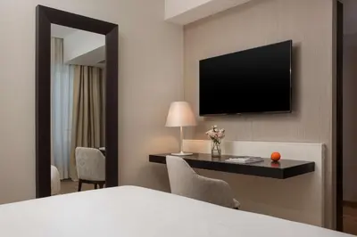 a hotel room with a bed and a television on a wall at NH Collection Palermo Palazzo Sitano in Palermo
