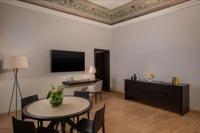 a living room with a table and a tv at NH Collection Palermo Palazzo Sitano in Palermo