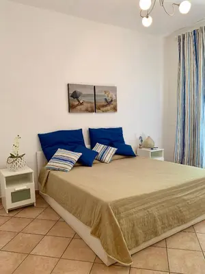 a bedroom with a large bed with blue pillows at Coral sea in San Vito lo Capo