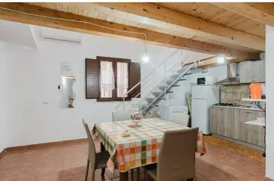 a kitchen with a table with chairs and a staircase at La casa di Anita nel cuore di Segesta in Calatafimi