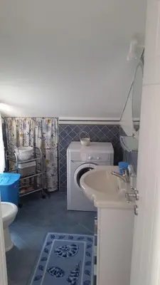 a bathroom with a washing machine and a sink at Mansarda Camelie via dei Normanni, 45 in Campofelice di Roccella