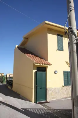 a house with a green door on a street at La Casa Gialla in Trabia