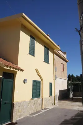 a house with green shutters on the side of it at La Casa Gialla in Trabia