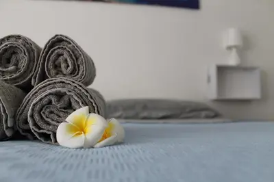 a pile of towels and a flower on a bed at Casa Vacanza Peppino! in Palermo
