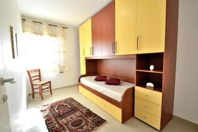 a bedroom with a bed with yellow cabinets and a chair at Villa Bianca e Villa Arancio in Alcamo