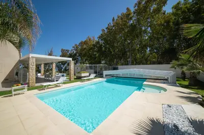 a swimming pool in a yard with a patio and trees at Villa Perla del Mare in Alcamo Marina