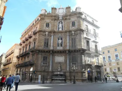 a large stone building with a clock on it at 4You in Palermo