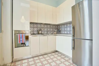 a kitchen with white cabinets and a stainless steel refrigerator at KMC suites - Yellow in Palermo