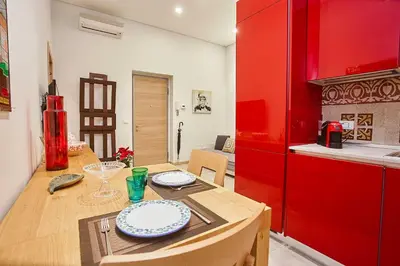 a kitchen with a wooden table and a red refrigerator at KMC suites - Red in Palermo