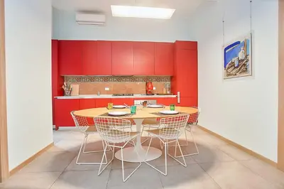 a kitchen with a table and chairs and red walls at KMC suites - Purple in Palermo