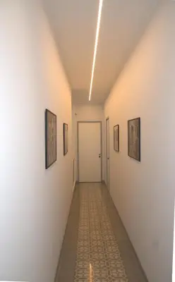 a corridor of a hallway with paintings on the walls at KMC suites - Purple in Palermo