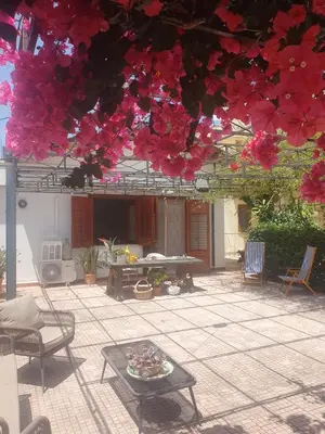 a patio with a table and some pink flowers at La depandance di Villa Rosa locazioni brevi in Mondello