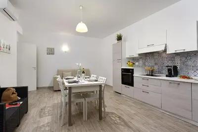 a white kitchen with a white table and a table and chairs at Casa Francesco in San Vito lo Capo