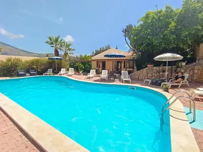 a swimming pool with chairs and umbrellas at Hotel Grotticelli in Scopello