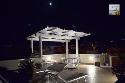 a gazebo with chairs and tables on a balcony at night at Appartamento Le Ginestre in San Vito lo Capo
