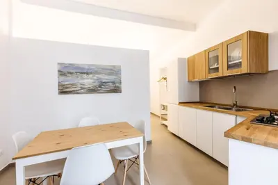 a kitchen with a wooden table and white cabinets at Loft Piazza Marina Family by DomuSicily in Palermo
