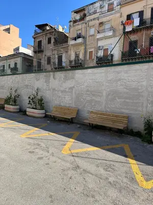 two benches in a parking lot next to a wall at Gò Gò House in Palermo