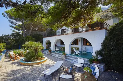 a house with a swimming pool and some chairs at Villa Majus in Porticello