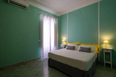 a bedroom with a bed with green walls and a window at Mille e una Notte / Station Apartment in Palermo