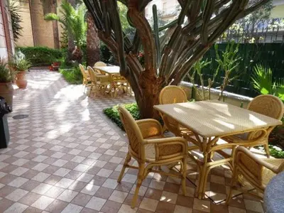 a patio with a table and chairs and a tree at Hotel Villa Archirafi in Palermo