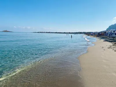 a beach with people swimming in the water at casa delle rose in Isola delle Femmine