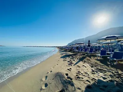 a beach with chairs and umbrellas and the ocean at casa delle rose in Isola delle Femmine