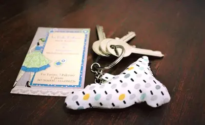 a pair ofkey chains with a wedding invitation and a shoe key chain at La Bella Balla-rò Rooms in Palermo