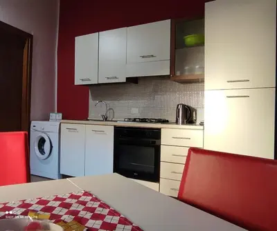 a kitchen with white cabinets and a table and red chairs at Casa Samu in Palermo