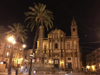 an old building with a palm tree in front of it at Elegante appartamento in centro in Palermo