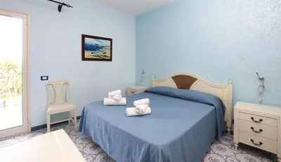 a blue bedroom with a bed and a chair at Cala Dell'Arena in Macari