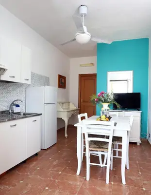 a kitchen with a white table and chairs and a blue wall at Cala Dell'Arena in Macari