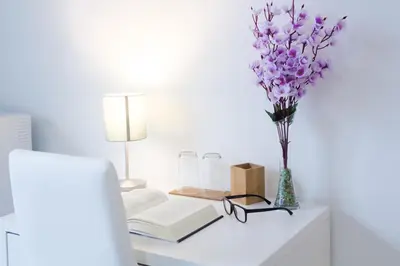 a desk with a vase of purple flowers and books at Darrè in Palermo