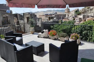 a balcony with chairs and tables and a view of a city at Villetta in Centro Storico in Caccamo