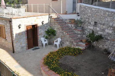 a patio with two chairs and a staircase with flowers at Villetta in Centro Storico in Caccamo