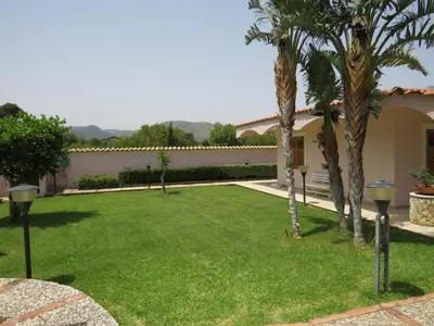 a yard with palm trees and a house at Villa Rosada in Castellammare del Golfo