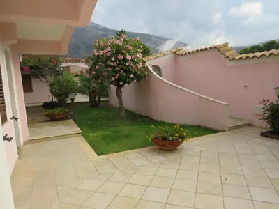 a house with a patio with a yard with flowers at Villa Rosada in Castellammare del Golfo