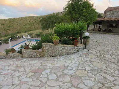 a stone patio with a retaining wall and a pool at Casale Giulietta in Scopello