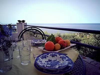 a table with plates of fruit on a balcony at Villa Mediterranea in Scopello