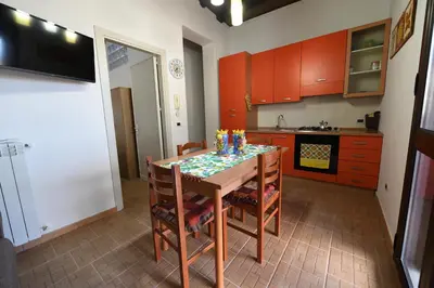 a kitchen with a table with chairs and red cabinets at By the Sea in Terrasini