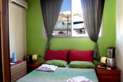 a bedroom with a bed with red pillows and a window at Bed & Breakfast Sweet Politeama in Palermo