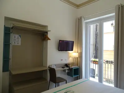 a room with a bed and a desk and a window at Le Quattro Stagioni - Rooms & Suites in Palermo