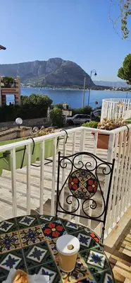 a balcony with a chair and a table with a view of the ocean at Ashur apartments in Mondello