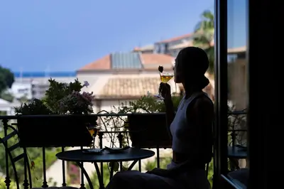 a woman sitting on a balcony drinking a glass of wine at BB 22 Charming Rooms & Apartments in Palermo
