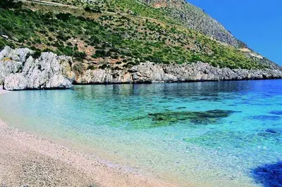 a beach with clear blue water next to a mountain at Casa Rachele ad Alcamo Marina in Alcamo Marina