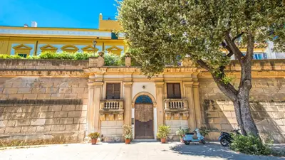 an old building with a tree in front of it at Amazing Sea View in Historic Building in Downtown by Wonderful Italy in Palermo