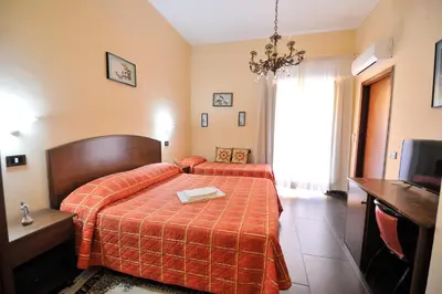 a bedroom with a bed with a orange bedspread at Hotel Piccolo in Termini Imerese